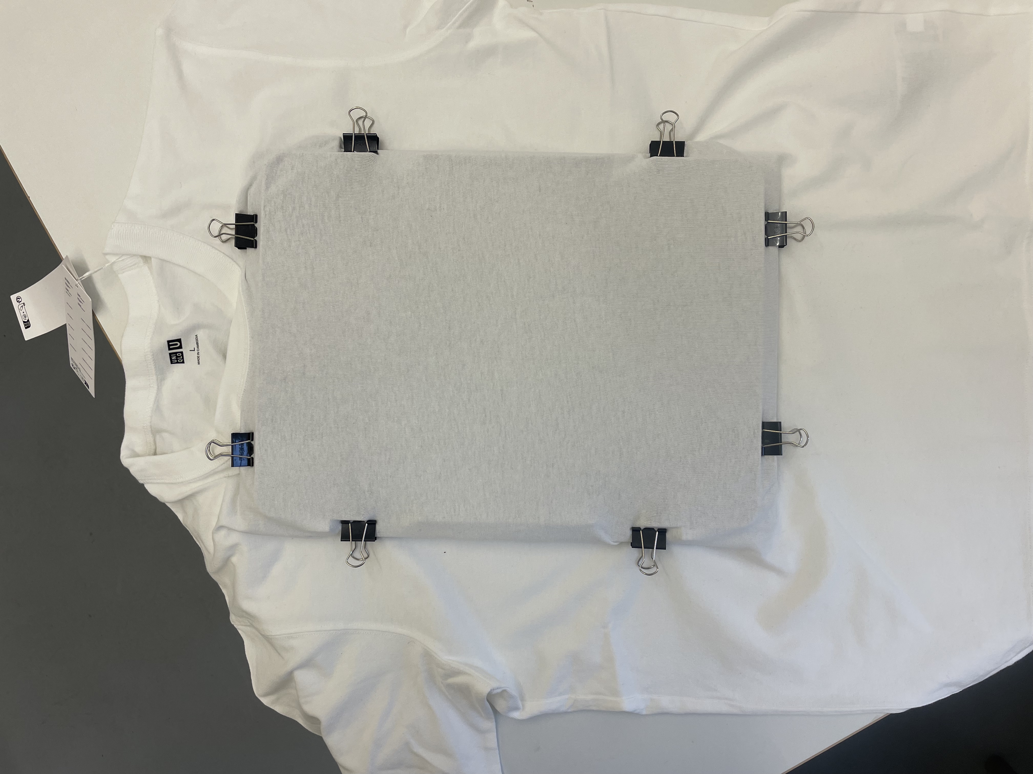 An image of the setup to print on cloth: a white t-shirt clamped to an underlying frame.